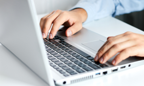 Person typing on a laptop with a focus on hands and keyboard